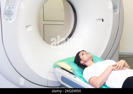 Il tecnico di scansione TC si affaccia sul paziente nello scanner di tomografia computerizzata durante la preparazione della procedura. Paziente donna che entra nello scanner TC. Foto Stock