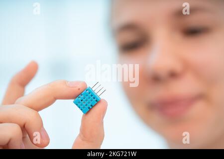 una giovane donna tiene in mano un sensore di gas velenoso per monitorare la qualità dell'aria Foto Stock