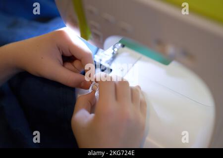 Le mani di una giovane ragazza che cucita su una macchina da cucire. Il concetto di piccola impresa, hobby, ricreazione domestica. Eco, zero rifiuti, riciclaggio. Foto Stock