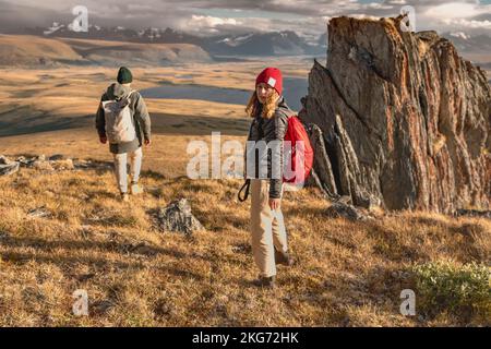 Giovane coppia cammina giù dopo l'escursione con zaini in montagna. Viaggi in montagna Foto Stock