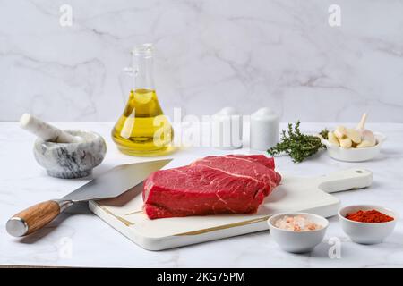 Bistecca di manzo cruda con spezie ed erbe sul tavolo da cucina Foto Stock