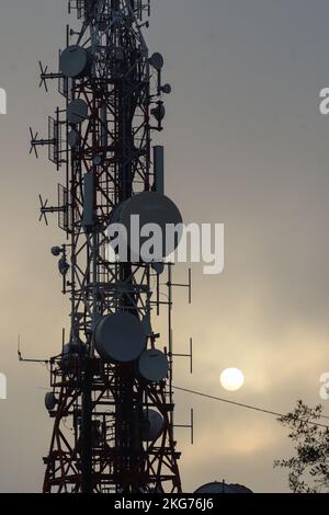 Televisione e telefono cellulare antenna al tramonto con il sole nella nebbia Foto Stock