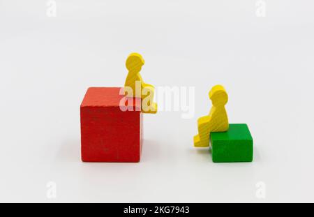 due figure di legno della gente che siede sulla parte superiore delle scatole alte e basse. rapporti sociali, rapporto maschio-femmina, differenze e figure. Banner Foto Stock