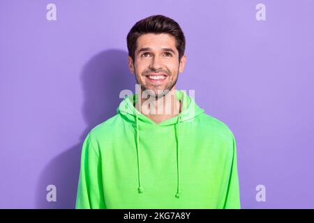 Ritratto di ragazzo ottimista bello con brunet acconciatura vestita felpa verde con cappuccio guardare spazio vuoto isolato su sfondo di colore viola Foto Stock