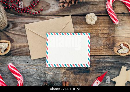Carta bianca, busta e decorazione di Natale su sfondo di legno, spazio copia. Foto Stock