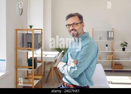 Uomo d'affari di mezza età di successo che guarda la fotocamera con espressione sicura sul suo volto. Foto Stock
