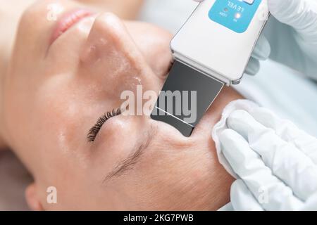 Primo piano dettaglio beautician medico fare cura della pelle peeling procedura di pulizia con ultrasuoni scrubber meccanico spatola al salone di bellezza clinica Foto Stock