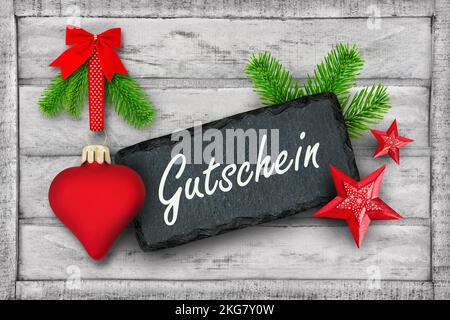 Gutschein für Weihnachten und Rote dekoration mit Herz, Tannenzweigen und Label auf Holz Foto Stock