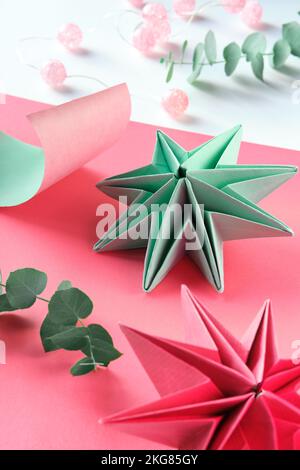 Vibranti stelle di carta origami, decorazioni natalizie fai da te fatte a mano. Stelle natalizie fatte da soli realizzate in carta colorata su sfondo stratificato. Fatto a mano Foto Stock