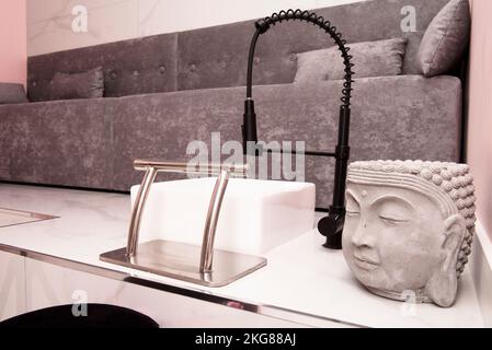 Lavabo con divani e testa di Buddha in un salone di bellezza dove si pratica pedicure Foto Stock