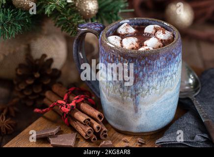 Tazza di cioccolata calda e marshmallows su un tavolo di legno con decorazioni natalizie sullo sfondo Foto Stock