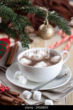 Tazza di cioccolata calda e marshmallows su un tavolo di legno con decorazioni natalizie sullo sfondo Foto Stock