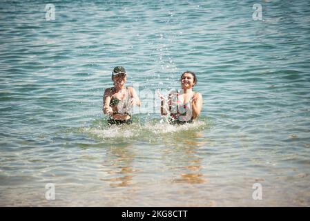 Due donne spruzzano acqua sulla spiaggia di Porto da barra a Salvador, Bahia Foto Stock