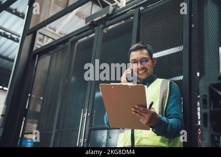 Felice lavoratore ingegnere asiatico maschio godere di lavorare in fabbrica industria. Foto Stock