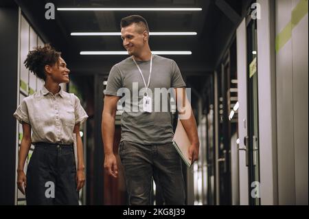 Due sorridenti e allegri dipendenti dei data center che parlano in movimento Foto Stock