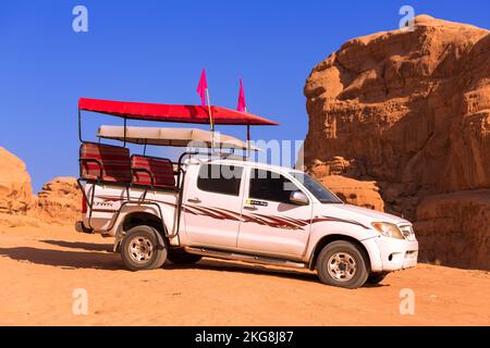 Giordania, Wadi Rum - 2 novembre 2022: Jeep beduina tour auto nel deserto con scogliera montagna rocciosa sullo sfondo Foto Stock