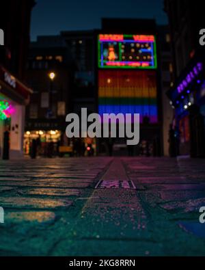 Un'immagine poco profonda sul campo ionico del cartello al neon Revue di Raymond a Soho, Londra, scattata di notte. Il pavimento è visto nel forgroun Foto Stock