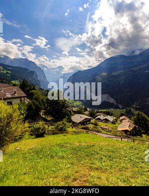 Un colpo verticale di case alpine sulle pendici delle Alpi Svizzere con una vista maestosa creste Foto Stock