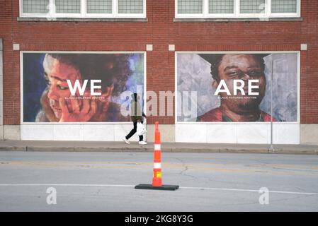 L'uomo passa per le foto di persone sul muro di mattoni rossi. Le vite nere contano. Foto Stock