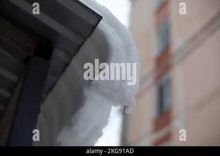 Neve sul tetto. Tettuccio con ghiaccio e neve sull'edificio. Dettagli di ghiaccio bordo. Foto Stock