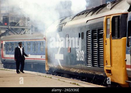 50031 'Hood' Class 50 visto fumare via a Londra Waterloo con 1V09, il 09,10 Waterloo - servizio Exeter, il 31st maggio 1991 - mentre la guardia si avvicina alla cabina per una rapida chat con il conducente. Foto Stock