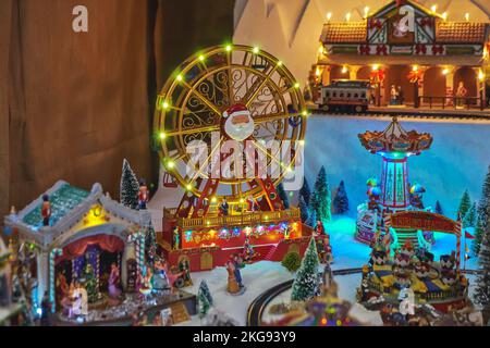 Ruota panoramica in miniatura e giostra con personaggi giocattolo nel parco invernale durante il mercatino di Natale Foto Stock