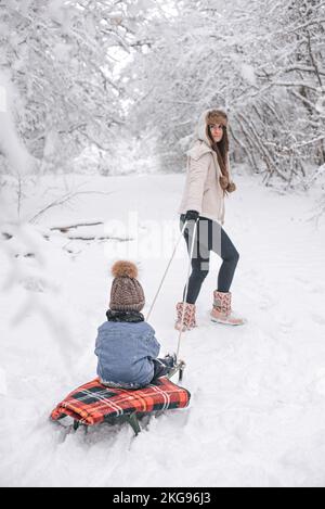 Mamma e figlio camminano nella neve nella foresta invernale. Foto Stock