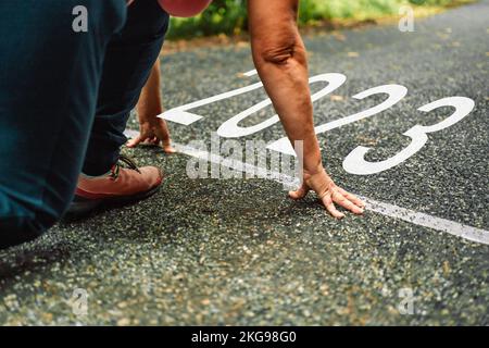 I numeri 2023 scritti sulla strada asfaltata e le corridori femminili stanno iniziando a correre pronti per il nuovo anno. Nuovo anno 2023 con nuove ambizioni, sfide, piani Foto Stock