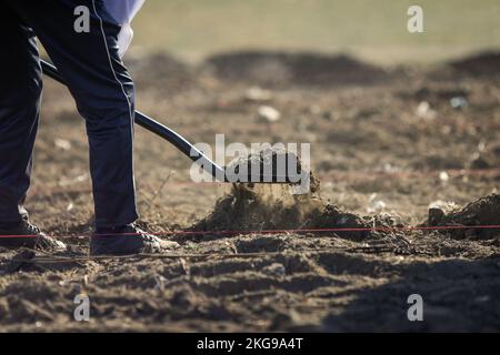 Dettagli con una persona che spala suolo asciutto, arido e polveroso durante un'attività di piantatura. Foto Stock