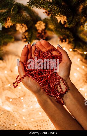 Composizione di Natale. Mani da donna con perle rosse Foto Stock