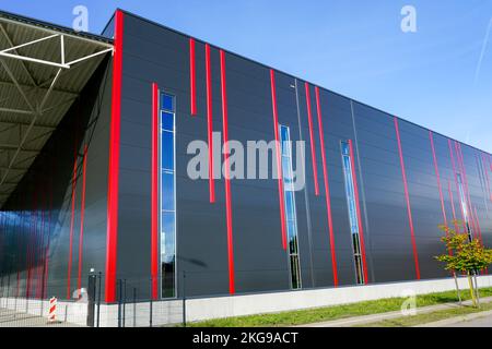 Facciata colorata con pannelli sandwich dal design moderno con strisce verticali rosse di un nuovo edificio industriale isolato termicamente con struttura in metallo Foto Stock