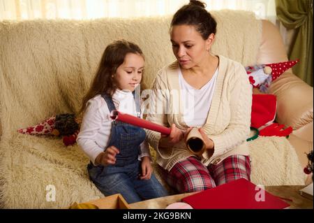 Affettuosa madre e figlia preparandosi per il nuovo anno o Natale, scelga la carta d'imballaggio per l'imballaggio del regalo nel paese Foto Stock