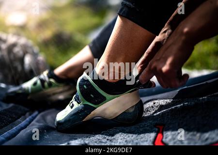 Descrizione: Donna sportiva mette su scarpa da masso nel pomeriggio. Passo Falzarego, Dolomiti, Alto Adige, Italia, Europa. Foto Stock