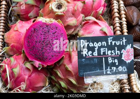 Frutti rossi del drago Ilocereus costaricensis o pitahaya un frutto tropicale. I frutti, un taglio a metà, sono in vendita in un mercato inglese di prodotti freschi Foto Stock