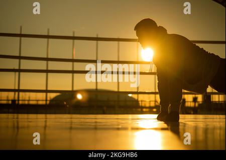 Giovane uomo caucasico che fa i push-up nel ring di boxe all'aperto al tramonto. Foto Stock