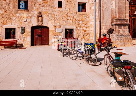 Pellegrini in bicicletta. Il monastero di San Juan de Ortega è un monumento romanico a Barrios de Colina, Montes de Oca, Burgos, Castilla y León, Spagna, Europa Foto Stock