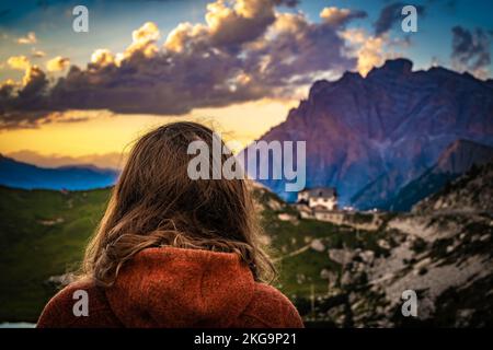 Descrizione: Donna sportiva in giacca esterna guarda bellissimo tramonto paesaggio montano al Rifugio Passo Valparola. Passo Falzarego, Dolomiti, TIR Sud Foto Stock