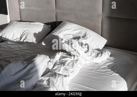 Letto vuoto stropicciato con coperta e cuscini, foto di sfondo del tempo di sonno Foto Stock