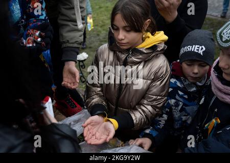 Una ragazza si vede raggiungere la sua mano per le caramelle da volontari. Le forze ucraine liberarono la capitale regionale meridionale Kherson per circa una settimana, dopo che la Russia si ritirò sulla riva sinistra del fiume Dnipro. La città che era sotto i 8 mesi di occupazione ancora non ha elettricità, acqua, cattivo segnale e approvvigionamento alimentare. Foto Stock