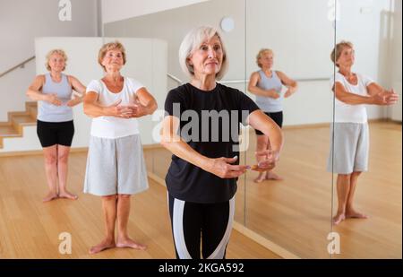 Le donne anziane che praticano la danza in studio sono in piedi nella prima posizione del balletto stand Foto Stock