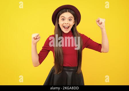 Adolescente eccitato, contento stupito e overjoyed emozioni. Ritratto di gioiosa bambina con mani sollevate. Adolescente caucasico urlando isolato su giallo Foto Stock