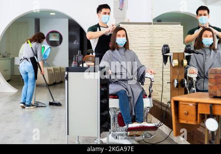 Professionale maschile parrucchiere in maschera taglio capelli donna Foto Stock