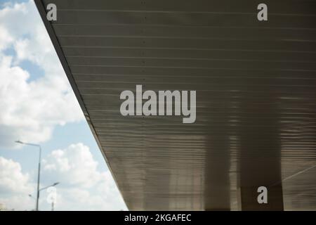 Soffitto della tettoia dell'edificio. Tetto sopra l'entrata. Riflessione nella superficie della parete. Dettagli architettonici. Foto Stock