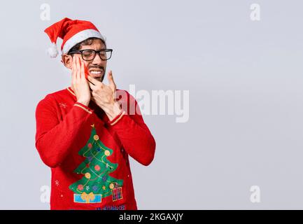 Uomo in maglione di natale con mal di denti, giovane uomo in cappello di natale con mal di denti isolato, uomo in cappello di natale in dolore toccando il suo dente. Christma Foto Stock