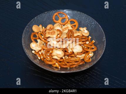 Un mucchio di snack salati in una ciotola di vetro Foto Stock