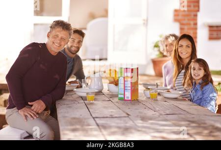 Il cibo ha un sapore migliore quando lo mangiate con la famiglia. Ritratto di una famiglia che fa colazione insieme fuori. Foto Stock