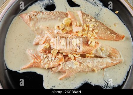 Pesce trota con nocciole e salsa di panna cotta al forno. Cucina francese gourmet. Giacitura piatta. Primo piano. Foto Stock