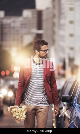 Non si può mai andare male con i fiori. un giovane uomo alla moda che cammina in città mentre tiene un bouquet di fiori. Foto Stock