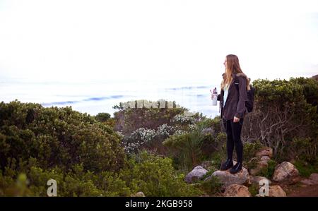 La vista è bellissima da qui. una giovane donna attraente godere la natura mentre fuori trekking. Foto Stock