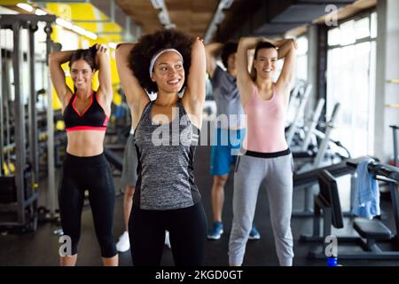 Gruppo multietnico di persone che si allenano in palestra. Allenatore e persone in forma sportiva che si allenano Foto Stock